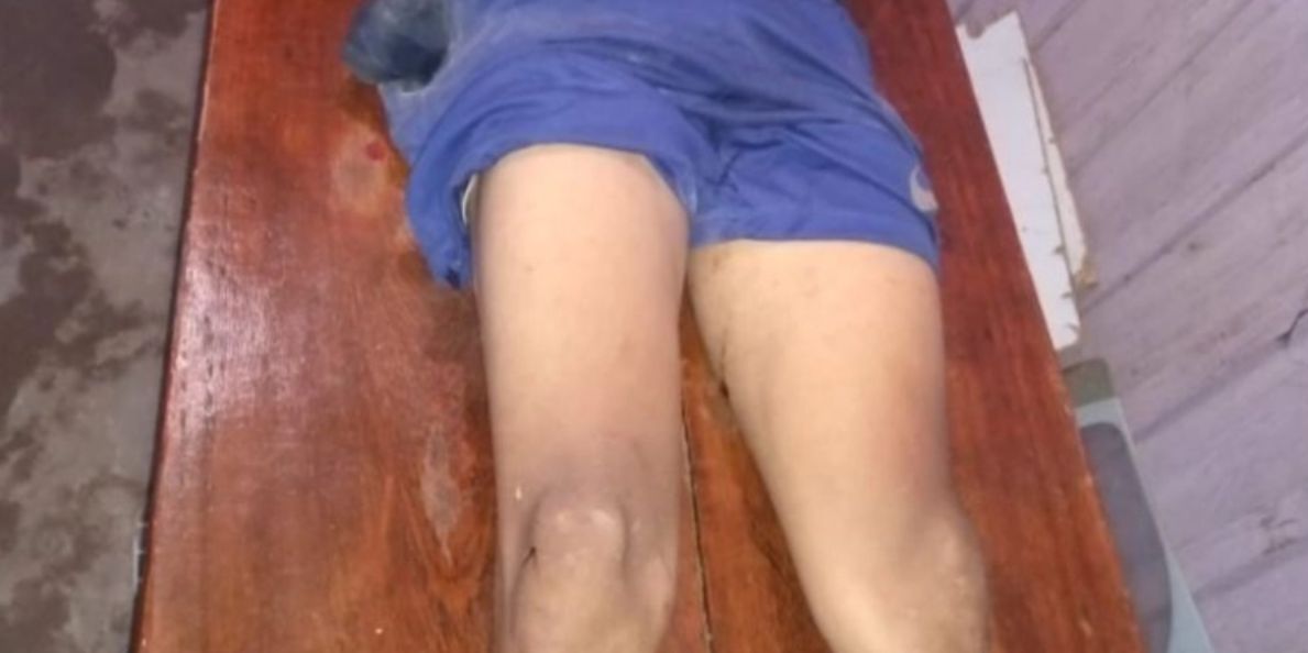 Mulher carrega corpo de filho morto na rua e o põe na mesa de casa